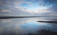 Reflecties op een nat strand bij zonsondergang