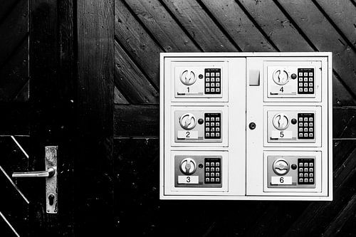 Black-and-white photograph of a door with door handle and lockers. by Wim Stolwerk