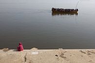 Indiase vrouw kijkt aan de oever van de Ganges in Varanasi naar een passerende boot met hindustaanse van Wout Kok thumbnail