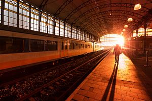 Silhouet van een man op treinstation tijdens zonsondergang van Rob Kints