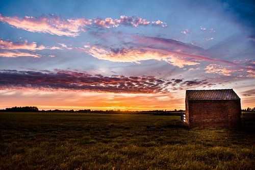 Sunset at a lonely cottage on a dike in west friesland