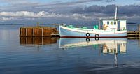 un bateau en bois aux tons pastel se reflète dans l'eau