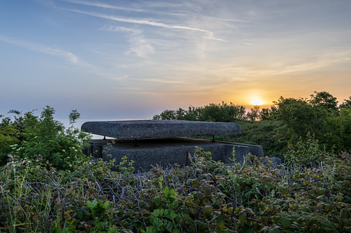 Atlantikwall-bunker bij Longues-sur-Mer tijdens zonsopkomst met uitzicht over de kust van Normandië en warm ochtendlicht boven historisch militair erfgoed.