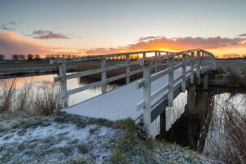Weiße Holzbogenbrücke mit einer Schneeschicht in der Morgensonne von Bram Lubbers