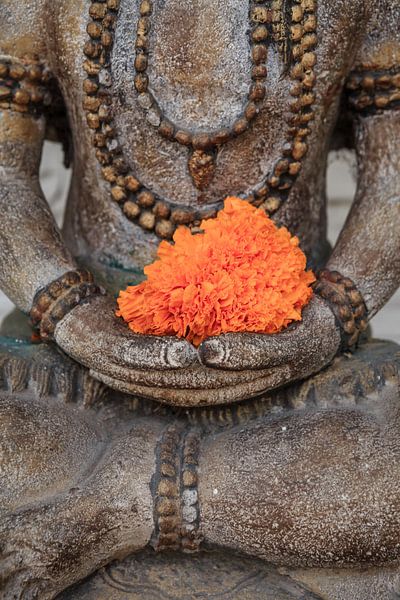 Schöner Buddha mit orangefarbener Blume irgendwo in Ubud. von Jeroen Langeveld, MrLangeveldPhoto