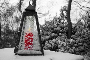 bougie rouge allumée dans un bougeoir sur une table dans la neige