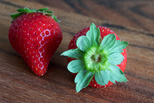 2 strawberries on a wooden board