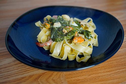 Fettuccini met spinazie en kaas roomsaus en zeevruchten geserveerd op een bord