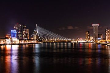 Rotterdam by Night - Erasmus Bridge and skylineDans cette photo, vous pouvez voir le pont Erasmus dans toute sa splendeur, étroitement éclairé sur la ligne d'horizon de Rotterdam. Les lumières de la ville se reflètent sur l'eau de la Meuse, donnant à l'image un aspect vivant. À gauche, on aperçoit les gratte-ciel modernes, à droite, l'imposant bâtiment De Rotterdam. L'ensemble forme un paysage urbain reconnaissable et puissant. sur Glenn Vlekke