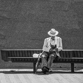 Man reading book on bench. by Eduardo