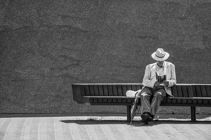Homme lisant un livre sur un banc. par Eduardo