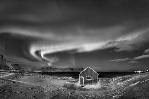 Houten huis met aurora borealis op de Lofoten eilanden in Noorwegen in zwart en wit.