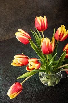 Red yellow tulips in glass vase by Iryna Melnyk