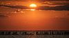 Zonsondergang Waddenzee met een mooie rij palen op de voorgrond. van Martijn van Dellen thumbnail