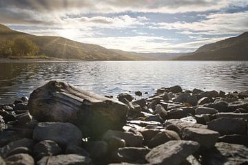 Rustig bergmeer met herfstheuvels en rotsen in het heldere water