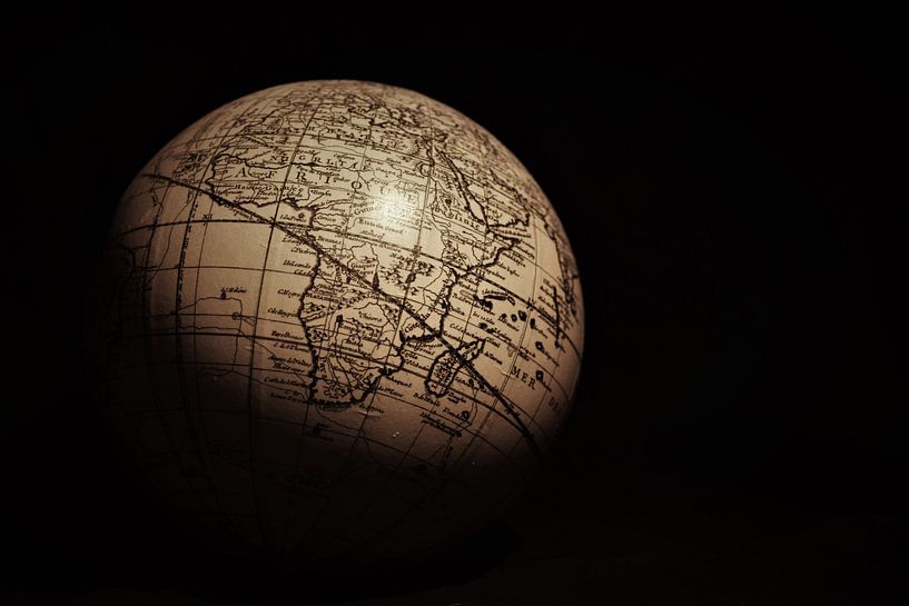 Teil eines Globus vor schwarzem Hintergrund von Maud De Vries