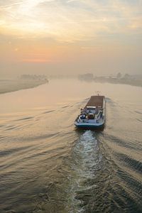 Schiff mit Massengütern in einem Sonnenaufgang über dem Fluss IJssel