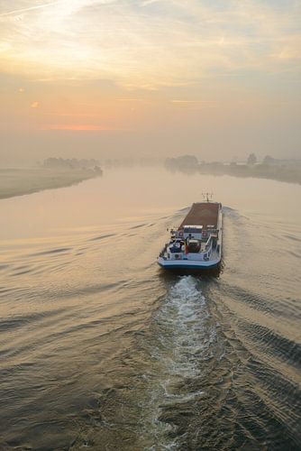 Navire transportant des marchandises en vrac dans un lever de soleil sur la rivière IJssel