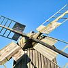 Alte hölzerne Windmühle in einer idyllischen Landschaft unter blauem Himmel von Martin Köbsch