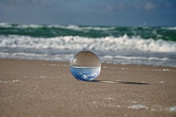 Blick durch die Glaskugel am Strand. Meer und Himmel im Hintergrund. von Martin Köbsch