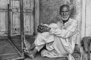 Angry looking man on veranda in Varansi India. One2expose Wout Kok by Wout Kok