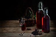 Zelfgemaakt sap van zwarte vlierbessen (Sambucus nigra) in flessen en bessen in een mandje op rustie van Maren Winter thumbnail