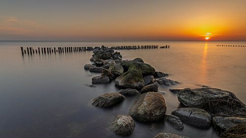 Golfbreker van stenen en palen in het IJsselmeer bij Enkhuizen tijdens mooie zonsopkomst