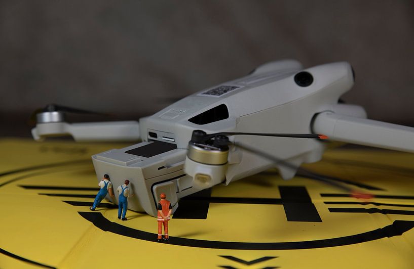 man die de batterij van een drone vervangt voor een nieuwe vlucht, de inspecteur controleert of het klopt van ChrisWillemsen