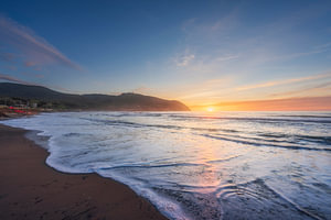 Wellen am Strand von Baratti bei Sonnenuntergang. Toskana, Italien