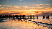 Paaltjes bij zonsondergang aan het strand van Truus Nijland thumbnail