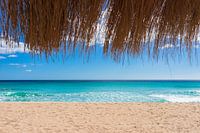Beautiful sand beach with turquoise sea water, sun, blue sky and straw umbrella