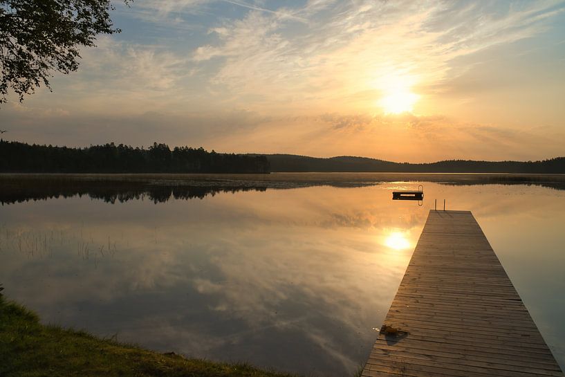 Footbridge, to the sunrise, reaching into a Swedish lake by Martin Köbsch
