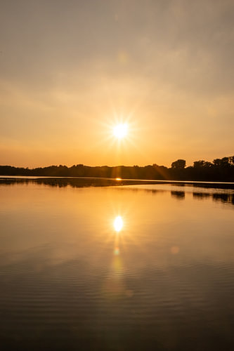 Romantische zonsondergang aan een idyllisch meer met zonneschijn en weerspiegeling