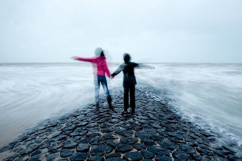 Zwei Kinder Hand in Hand auf Wellenbrecher im Meer von Remke Spijkers
