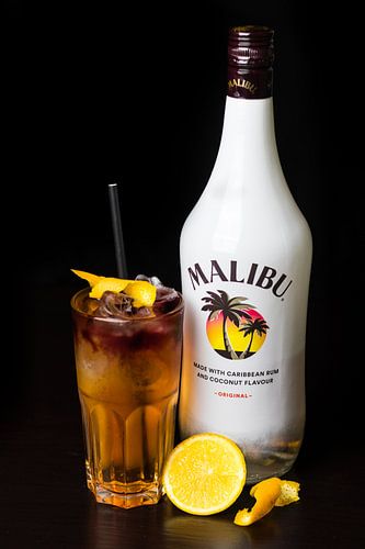 Malibu cocktail met sinaasappel als garnering en een zwarte achtergrond