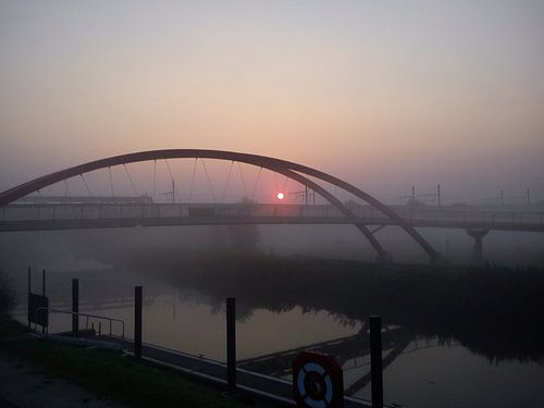 Zonsopgang langs de rivier (Dender, België) met brug. Lente.
