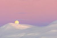 Roze zonsopkomst en maanondergang boven besneeuwde berg