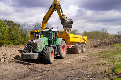 Tractor en graafmachine in actie