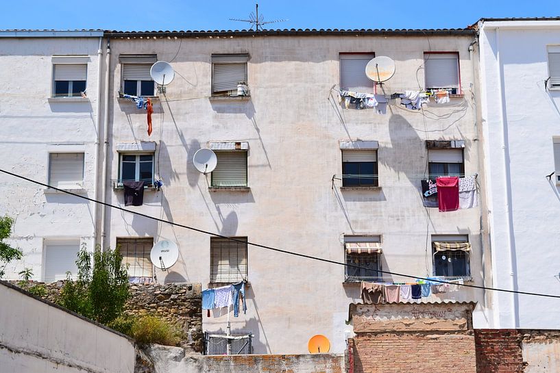 Weiße Fassade mit weißen Satellitenschüsseln und flatterndem Wachs unter strahlender spanischer Sonne und blauem Himmel von Studio LE-gals