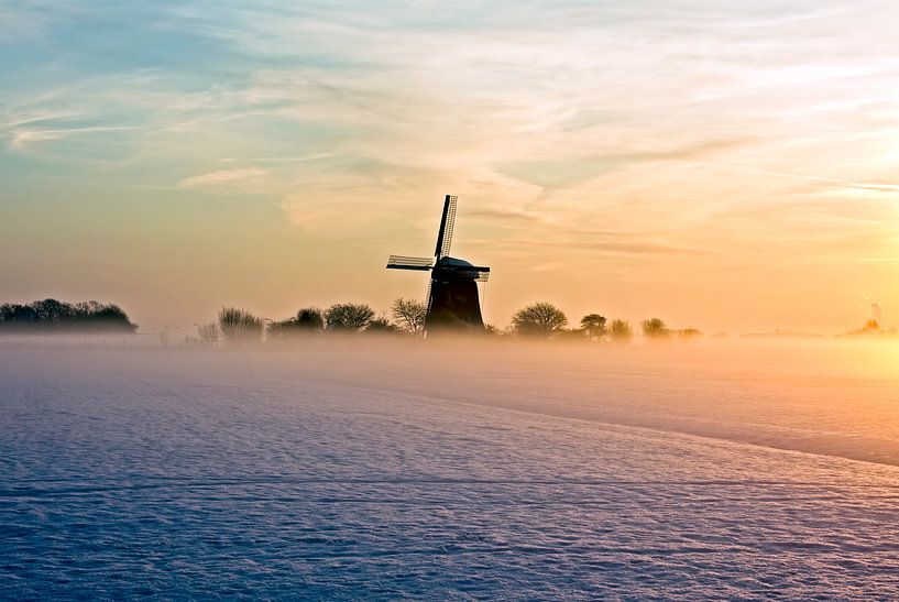 Traditionele hollandse molen in de mist en sneeuw op het platteland van Nederland bij zonsondergang van Eye on You