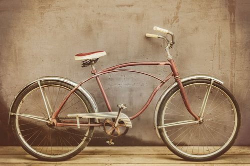 Vélo de croisière d'époque rouillé sur un plancher de bois