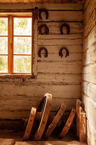 Wagon wheels and horseshoes in an abandoned barn in Sweden. by Maarten Visser