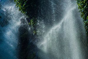 Sonnenstrahlen fallen durch die Tropfen eines Wasserfalls