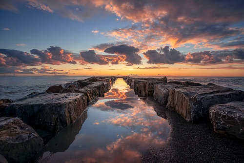 Spiegelung der Felsen im Meer bei Sonnenuntergang in Marina di Cecina, Italien