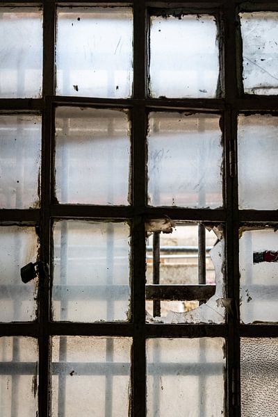 Zerbrochenes Fenster mit Gittern in einem verlassenen Gefängnis von Elly de Vries
