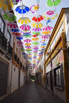 Vrolijke gekleurde paraplu's in een zonnig straatje van Studio LE-gals