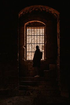 Man met pet voor tralies in een ruïne van een kasteel in Sidon, Lebanon van Moniek Kuipers
