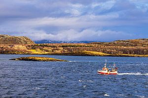 Felsen und Fischerboot im Winter nahe Sortland in Norwegen