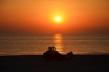 Tractor bij zonsondergang op het strand