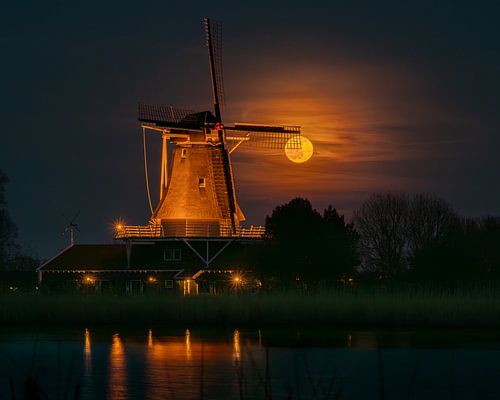 Volle maan schijnt door de wieken van molen De Leeuw in Anna Paulowna